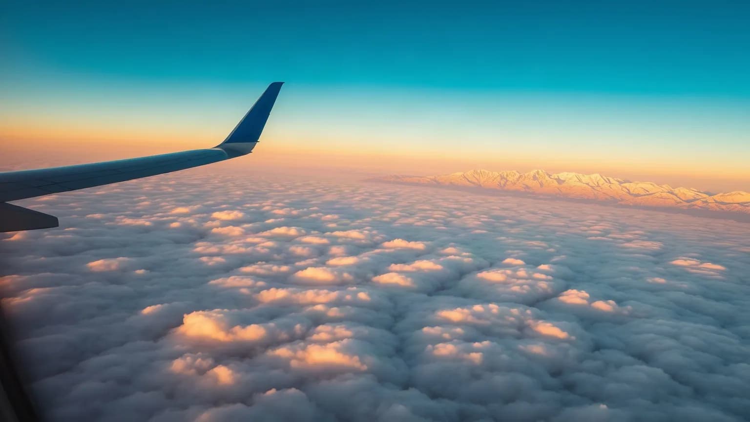 View from an aeroplane window of a wing above the clouds at sunrise