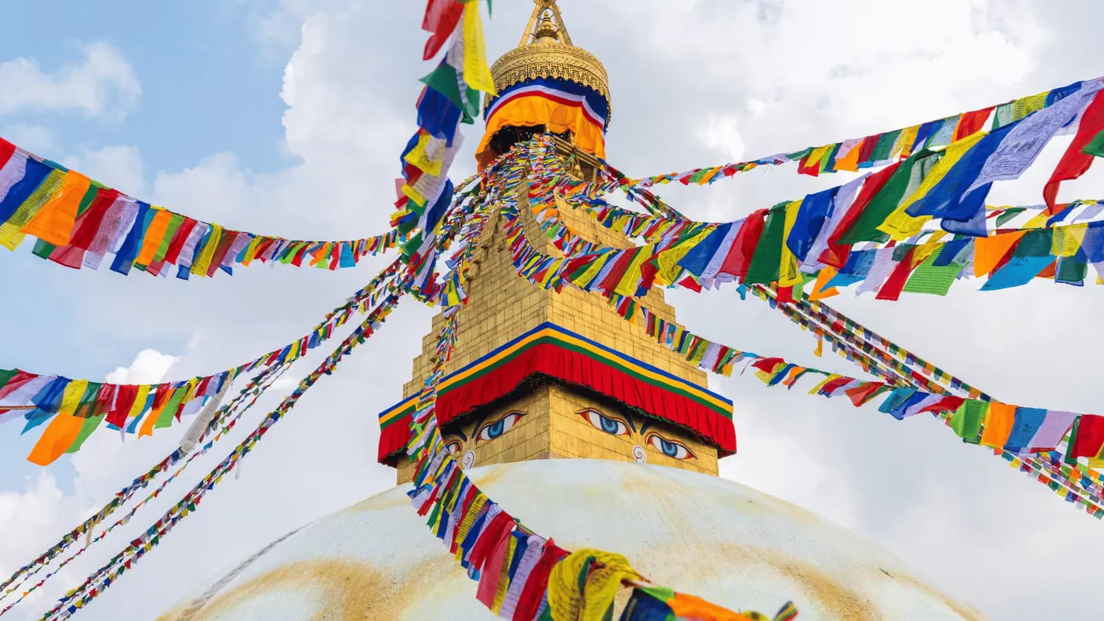 Prayer flags and the golden spire of a stupa in Kathmandu under a blue sky